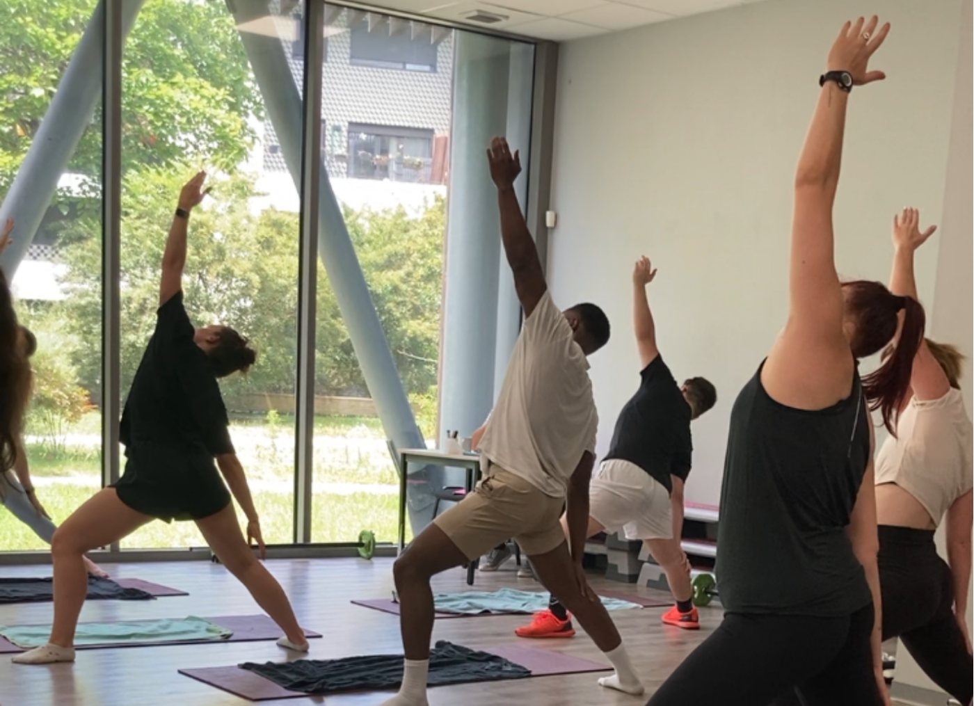 Cours collectif de sport-santé en studio lumineux, posture d'étirement latéral en groupe